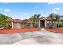 Spacious brick home with a circular driveway, palm trees, manicured landscaping, and a grand entrance with oversized columns at 2841 S Lloyd Ln, Kissimmee, FL 34744