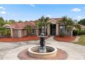 Stately brick home featuring a circular driveway, large fountain, mature landscaping, and grand entrance with columns at 2841 S Lloyd Ln, Kissimmee, FL 34744