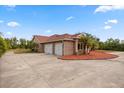 Detached garage with three bays and a side entry, surrounded by mature landscaping and a spacious paved driveway at 2841 S Lloyd Ln, Kissimmee, FL 34744