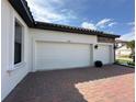 Attached two-car garage with white doors, black carriage lights, and brick accents at 2920 Agostino Ter, Kissimmee, FL 34746
