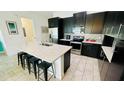 Modern kitchen boasts dark cabinetry, an island with seating, and stainless steel appliances at 349 Captiva Dr, Davenport, FL 33896