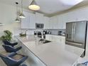 Modern kitchen featuring white cabinets, stainless steel appliances, quartz countertops, and breakfast bar seating at 703 Ocean Course Ave, Davenport, FL 33896