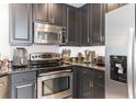 Modern kitchen with sleek stainless steel appliances, granite counters, and dark cabinets at 7503 Mourning Dove Cir # 101, Reunion, FL 34747