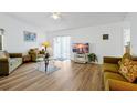 Bright living room featuring wood floors, neutral walls, comfortable seating and sliding glass door access to the lanai at 7807 Turkey Oak Ln, Kissimmee, FL 34747