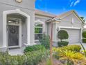 Close-up of front entry with landscaped garden, arched entryway, and gray two car garage at 12313 Prairie Plantation Way, Orlando, FL 32824