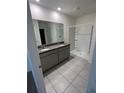Bathroom with double vanity, granite countertop, tiled floor and glass-enclosed shower at 1828 Buckeye Rd, Davenport, FL 33837