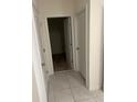 Hallway with multiple white doors, closet and neutral tile flooring at 1828 Buckeye Rd, Davenport, FL 33837