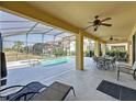 Spacious covered patio with ceiling fans, outdoor dining, and lounge seating overlooking the pool and green space at 219 Rosso Dr, Davenport, FL 33837
