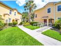 Exterior view of the condos featuring lush green grass, sidewalks and tropical landscaping at 2736 Oakwater Dr, Kissimmee, FL 34747