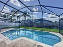 Inviting in-ground pool with screened enclosure, surrounded by lush backyard and privacy fence at 8019 Indian Creek Blvd, Kissimmee, FL 34747
