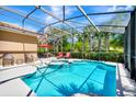Inviting screened-in pool with a hot tub, lounge chairs, and tropical landscaping for ultimate relaxation at 4416 Acorn Ct, Davenport, FL 33837