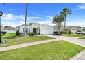 Inviting single-story home with a brick driveway, two-car garage, and lush green lawn and landscaping at 4796 Cumbrian Lakes Dr, Kissimmee, FL 34746