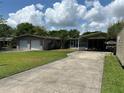 View of the detached two-car garage, home, and covered carport with long driveway at 930 Aultman Rd, Kissimmee, FL 34744