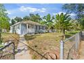 Quaint home with gray exterior, a white porch, and a fenced front yard at 1024 Cohassett Ave, Lake Wales, FL 33853