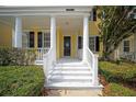 Inviting front porch with classic white pillars and stairs leading to the colorful front door at 1115 Mosaic Dr, Celebration, FL 34747