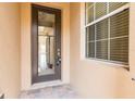 A welcoming front door features a glass panel, with a window on the side, on a charming textured exterior and stone tile entry at 2376 Palm Tree Dr, Kissimmee, FL 34759
