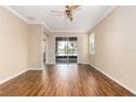 An airy living room boasts wood floors, a ceiling fan, crown molding, and sliding glass doors to a screened lanai with a water view at 2376 Palm Tree Dr, Kissimmee, FL 34759