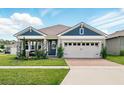 Charming single-Gathering home featuring a brick driveway, a two-car garage and stylish blue accents at 3443 Florigold Grove St, Clermont, FL 34711
