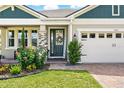 Inviting entryway featuring a decorative wreath, colorful flowers, and stone columns at 3443 Florigold Grove St, Clermont, FL 34711