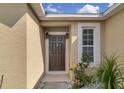 Welcoming front door with decorative sidelights and lush landscaping at 561 Lake Cummings Way, Lake Alfred, FL 33850