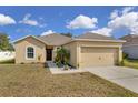 Inviting home with manicured lawn and a two-car garage, creating a warm welcome at 561 Lake Cummings Way, Lake Alfred, FL 33850