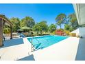 Sparkling pool surrounded by patio, lush landscaping, and a charming pergola at 6464 Timberwind Pl, Orlando, FL 32818