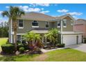 Inviting two-story home with a three-car garage, lush tropical landscaping, and a well-manicured lawn at 8571 La Isla Dr, Kissimmee, FL 34747