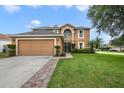 Charming two-story home with a well-manicured lawn and two car garage in daylight at 102 Royalty Cir, Sanford, FL 32771