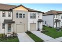 Charming townhome featuring a garage, blue front door, and manicured lawn in a modern community at 1067 Plantation Ln, Davenport, FL 33896