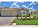 Charming villa featuring stone accents, a two-car garage, and well-maintained landscaping under a sunny, partly cloudy sky at 1082 Blackwolf Run Rd, Davenport, FL 33896