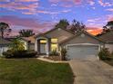 Inviting single-story home with a well-maintained lawn and an attached two-car garage at dusk at 149 Imperial Oak Ct, Davenport, FL 33896