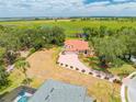 Expansive aerial view showcases the property's red-tile roof, brick driveway, lush surroundings, and access to a serene lake at 1654 Marina Lake Dr, Kissimmee, FL 34744