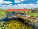 A screened dock with a red tile roof holds a boat covered in a tarp with a walkway out to the dock at 1654 Marina Lake Dr, Kissimmee, FL 34744