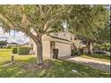 Two-story home with a well-manicured lawn, a stone-accented facade, and mature trees creating a shaded area at 214 Tupelo Cir, Davenport, FL 33897