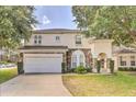 Beautiful two-story home boasts a well-manicured lawn and a stone-accented facade under a tree-shaded sky at 214 Tupelo Cir, Davenport, FL 33897