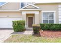 Well-maintained front exterior with a brick walkway, manicured bushes, and a two-car garage at 223 Cadiz Loop, Davenport, FL 33837