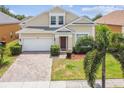 Charming two-story home featuring a brick driveway, manicured landscaping, and an attached garage at 223 Cadiz Loop, Davenport, FL 33837