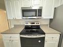 Close up of black stovetop and stainless steel microwave in a white kitchen at 2330 Prime Cir # A, Kissimmee, FL 34746