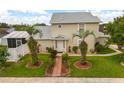 Inviting home featuring a well-kept lawn, symmetrical landscaping, and a charming brick walkway at 2411 Parsons Pond Cir, Kissimmee, FL 34743