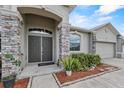 Inviting front entry with stone pillars and manicured landscaping with mulch and lush foliage at 491 Majestic Gardens Blvd, Winter Haven, FL 33880