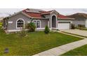 Beautiful single Gathering home with a red roof, green grass and an attached garage at 5418 Crepe Myrtle Cir, Kissimmee, FL 34758