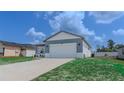 Single-Gathering home with a concrete driveway, two-car garage, and a well-maintained lawn under a bright blue sky at 109 Lily Ln, Poinciana, FL 34759