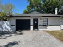 Inviting single-story home featuring a dark garage door, brick details and a new white perimeter fence at 1256 S Bumby Ave, Orlando, FL 32806