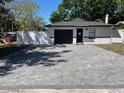 Well-maintained single-story home featuring a dark garage door, new white perimeter fence, and paved driveway at 1256 S Bumby Ave, Orlando, FL 32806