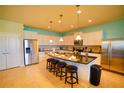 Bright kitchen featuring white cabinets, stainless steel appliances, a large island with bar stools, and modern pendant lighting at 2147 Tripoli Ct, Kissimmee, FL 34747