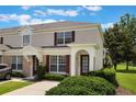 Charming two-story townhome with beige exterior, red shutters, and well-maintained landscaping at 2322 Silver Palm Dr, Kissimmee, FL 34747