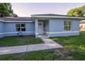 Close up of the front door and window of the light blue single story house on green lawn at 3661 Se 131St Pl, Belleview, FL 34420