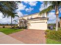 Two-story home showcasing landscaping, brick driveway, two-car garage and palm trees at 389 Yellow Snapdragon Dr, Davenport, FL 33837