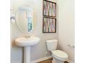 Cozy half bathroom featuring a pedestal sink, toilet, decorative mirror, and stylish framed artwork at 5228 Bee Balm St, Lake Hamilton, FL 33851