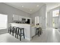 Eat-in kitchen features stainless appliances, sleek white cabinetry, and breakfast bar seating at 553 Bailey Cir, Davenport, FL 33897